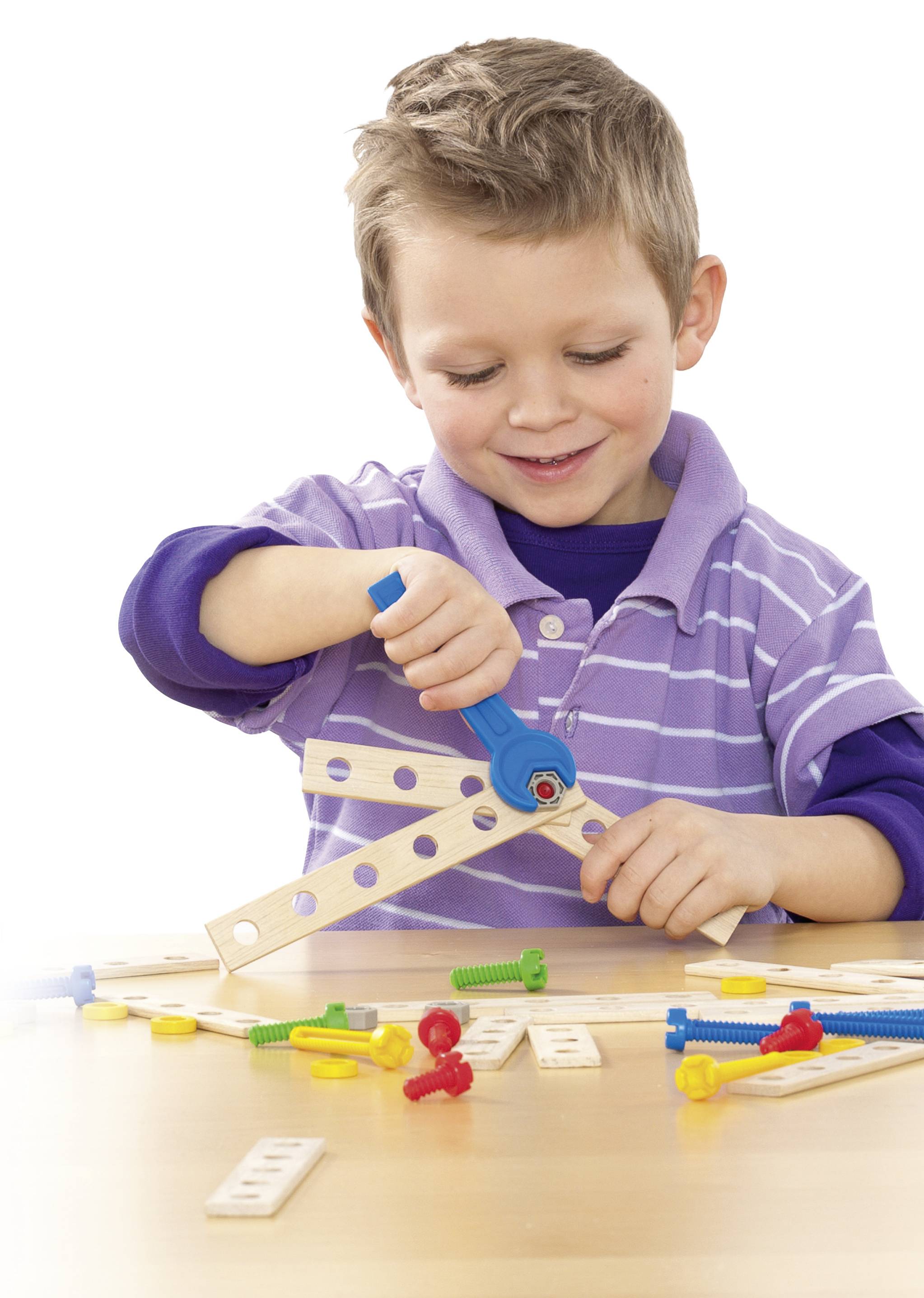 Een jongen speelt geconcentreerd met een bouwset en schroeft onderdelen in elkaar. Verschillende gekleurde kunststofschroeven liggen op tafel.