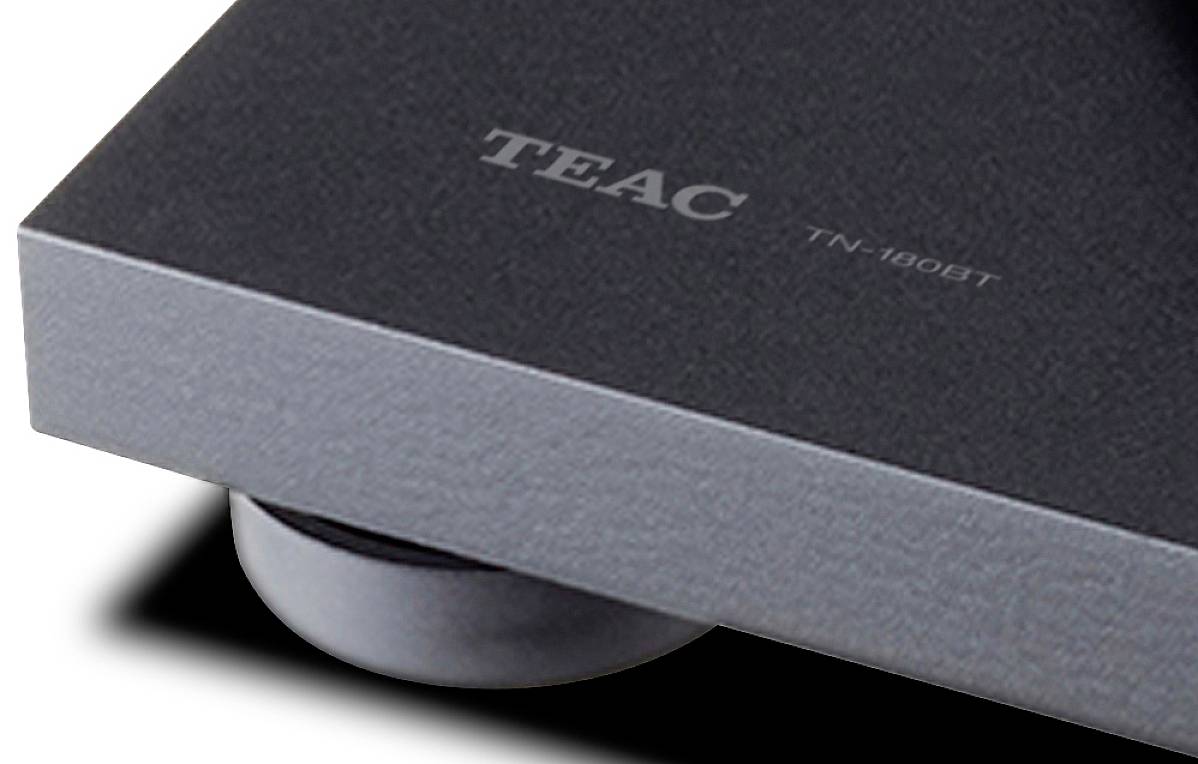Platenspeler-hoek met het 'TEAC TN-180BT' logo zichtbaar, toont een deel van het apparaat en de standaard.