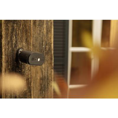 Een beveiligingscamera is zijdelings bevestigd aan een houten muur, met een raam op de achtergrond.