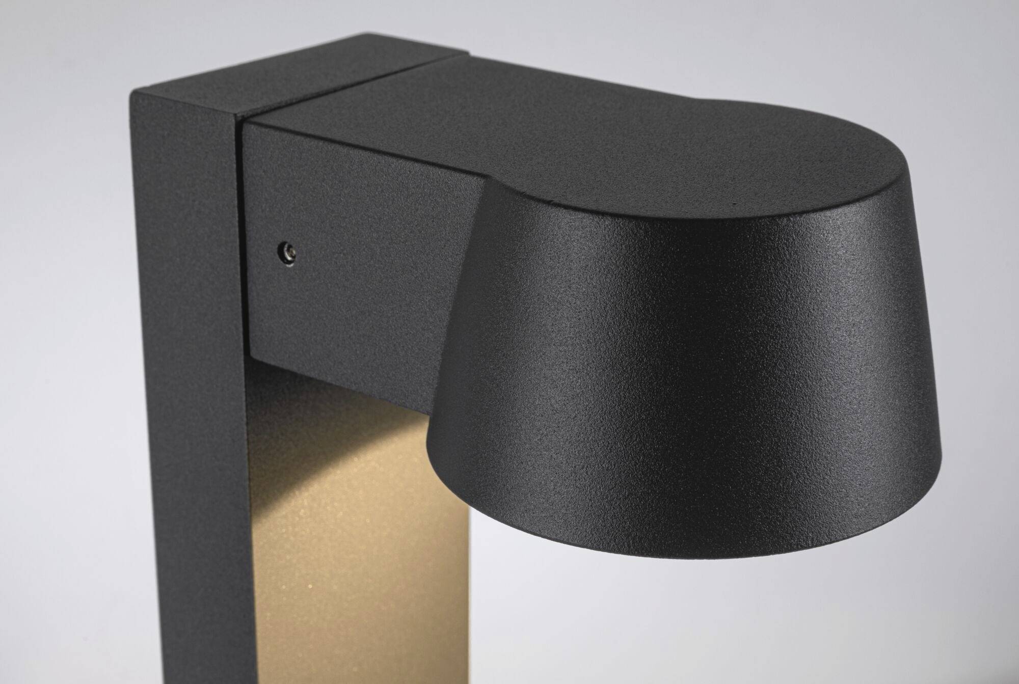 Moderne zwarte buitenlamp in close-up, gemonteerd aan een muur. Hij heeft een strak, hoekig ontwerp zonder zichtbare gloeilamp.