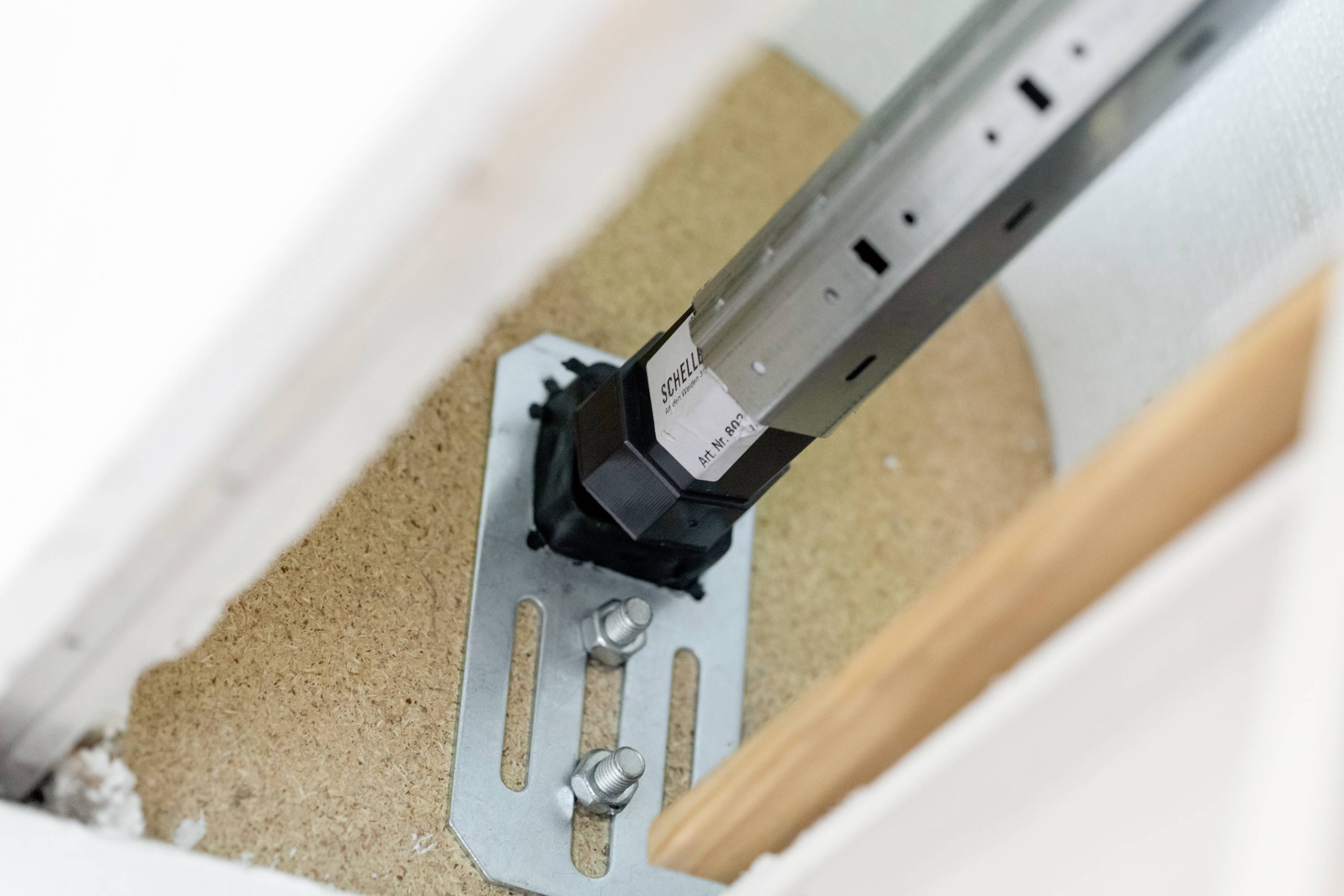 'Telescoopsteun in de hoek van een bouwproject, gemonteerd op een vloerplaat met schroeven. Ondersteuningsgereedschap voor bouw of montage.'