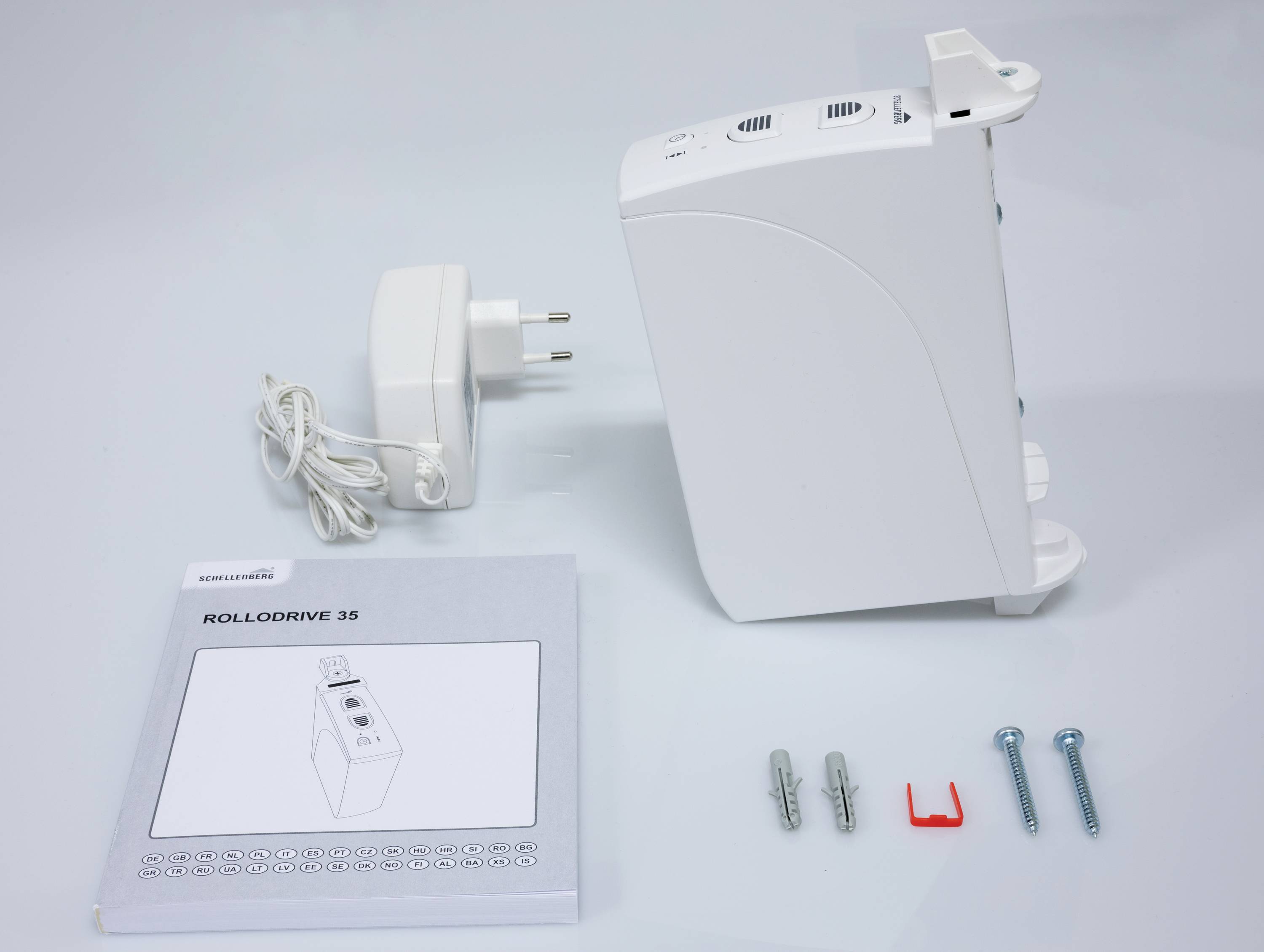 Rolluikmotor met voedingsadapter, handleiding, schroeven en pluggen voor installatie.