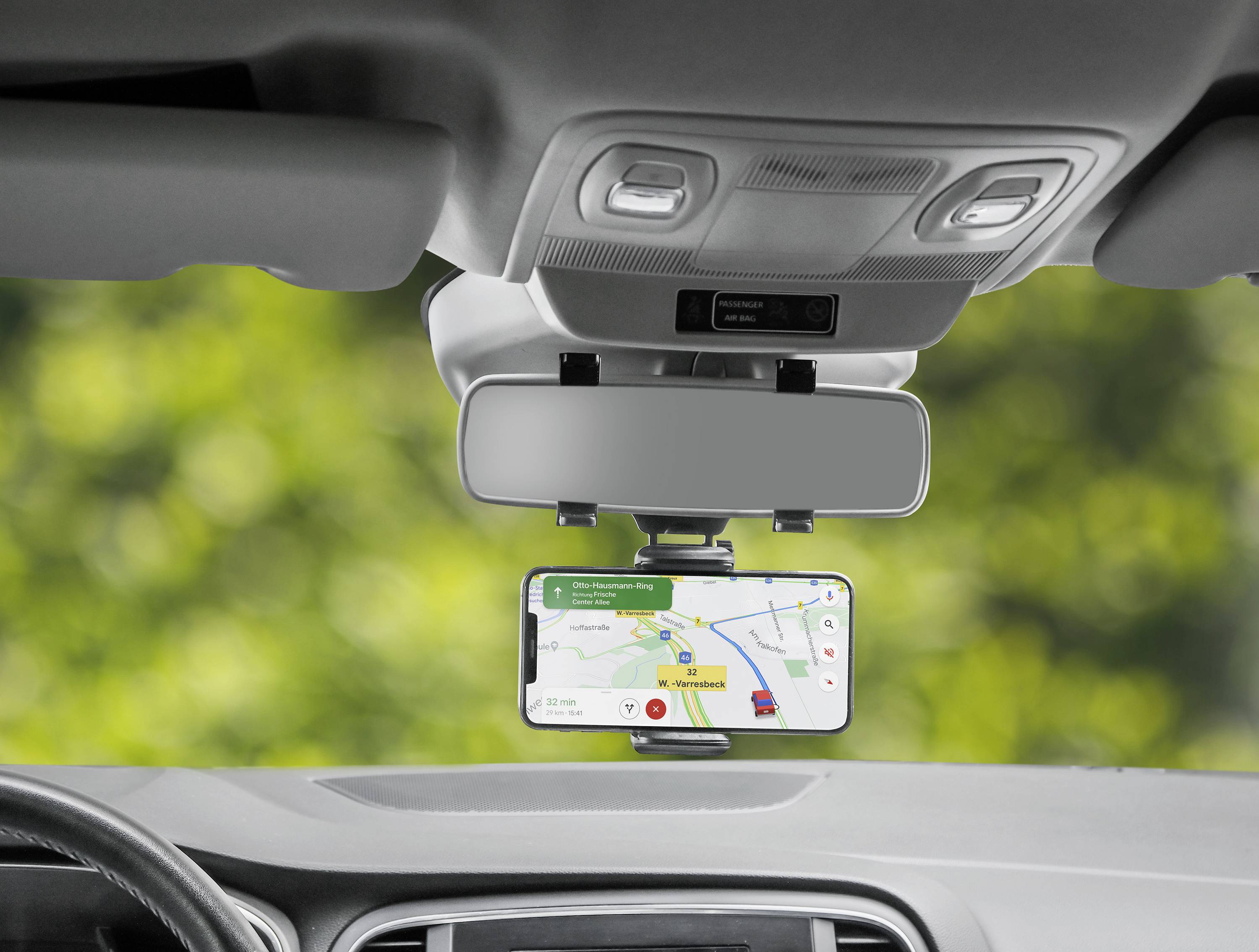 Een smartphone in een autohouder toont een navigatie-app met een route en bestemmingsinformatie, zichtbaar door de voorruit.