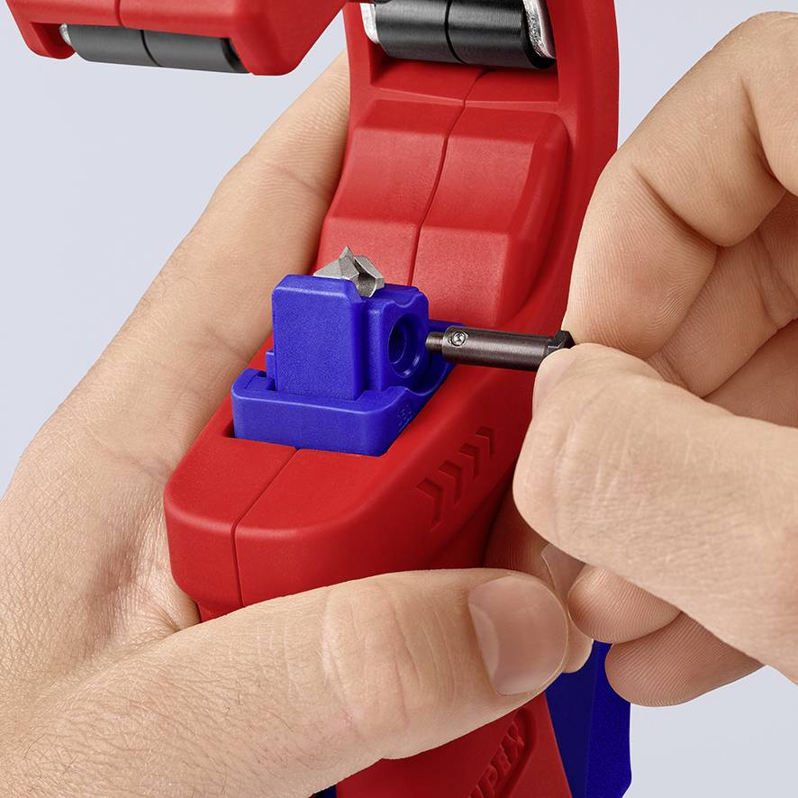 Rode kabelstriptang met blauwe instelbare mechanisme, wordt vastgehouden door één hand. Een potlood wordt in de tang gelegd.