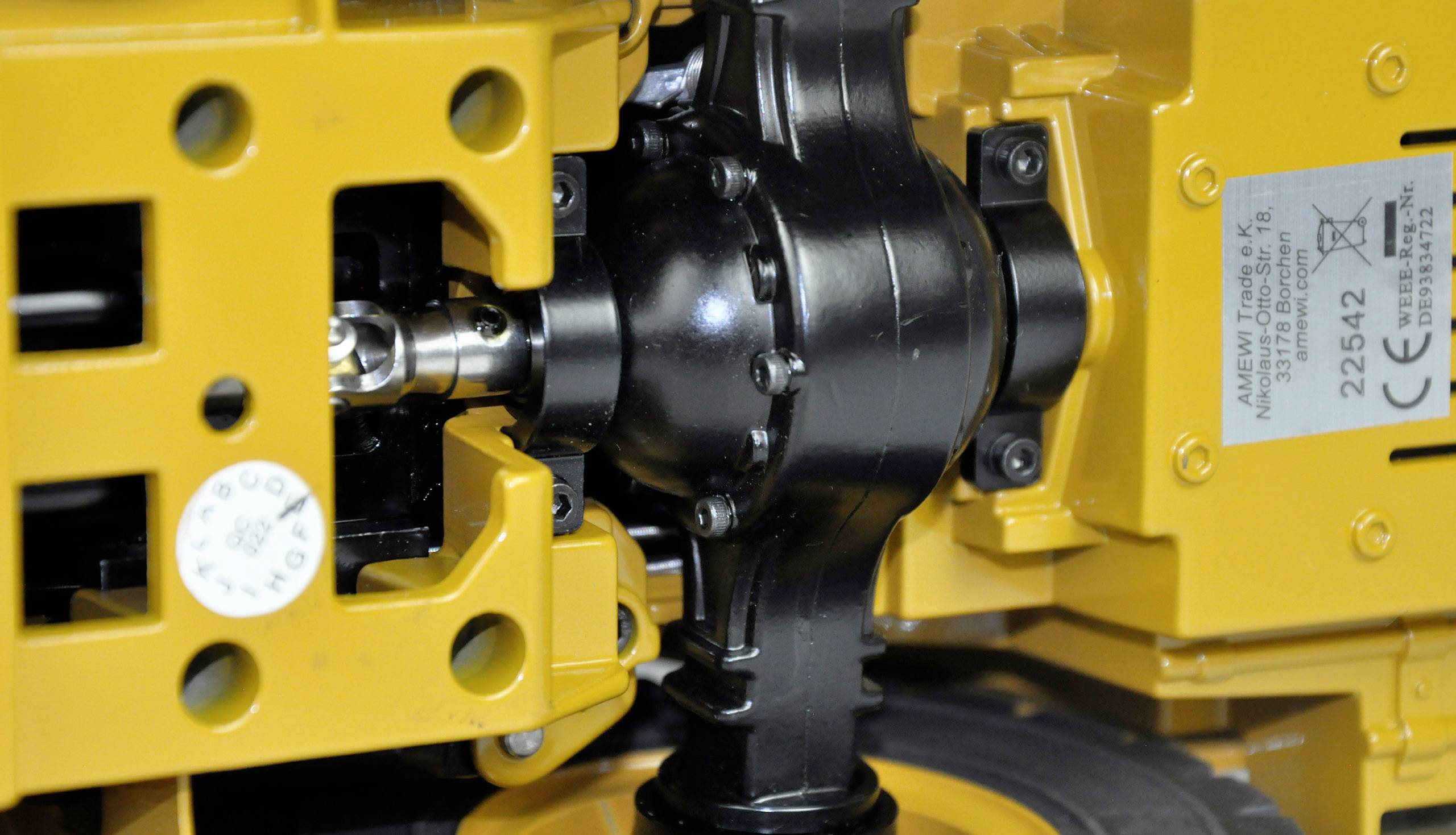 Geel mechanisch apparaat met zichtbare tandwielen en metalen componenten, waarschijnlijk onderdeel van een groter industrieel systeem.