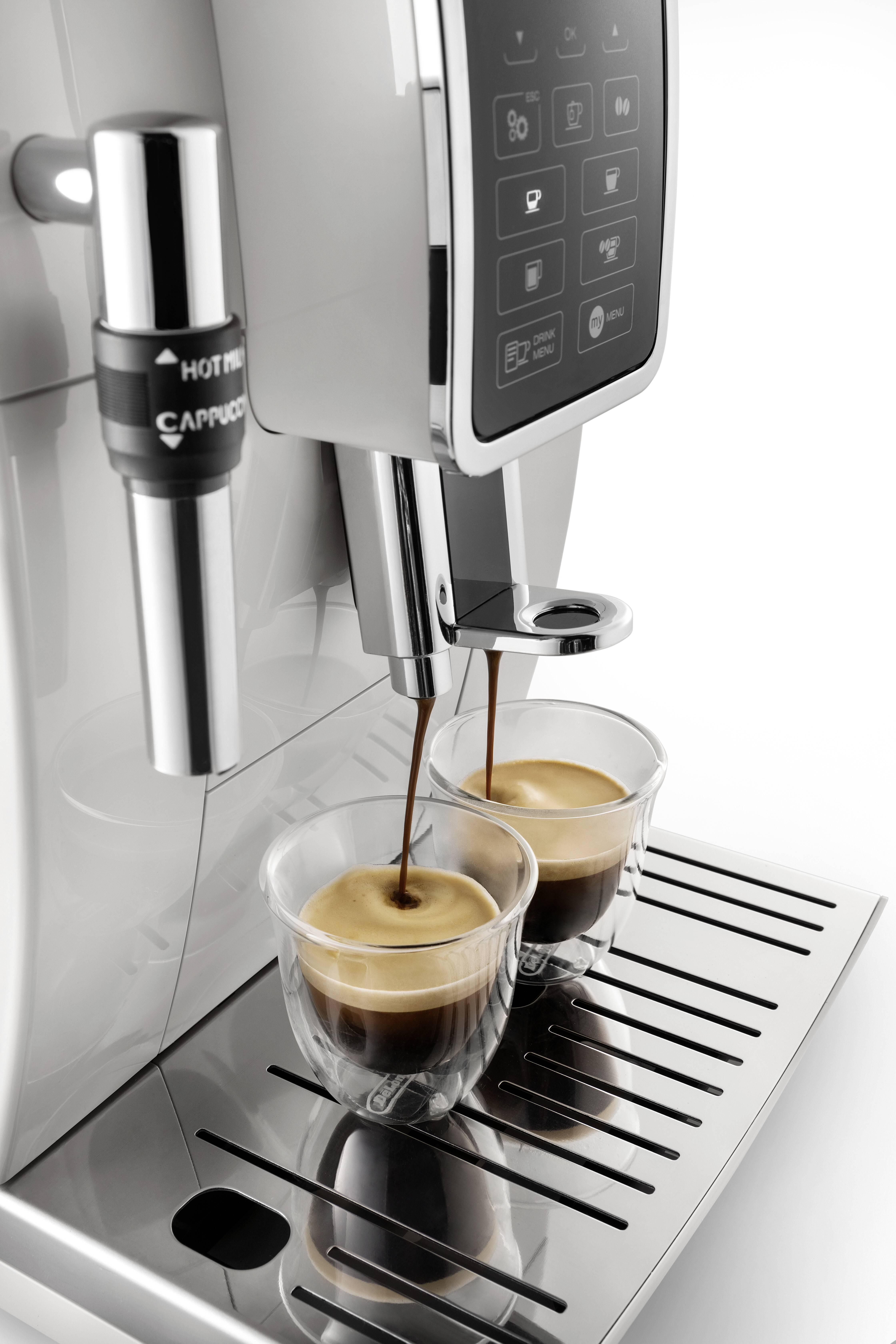 Twee espressokopjes worden onder de uitloop van een zilveren espressomachine geplaatst. Crèmekleurige espresso wordt ingeschonken.
