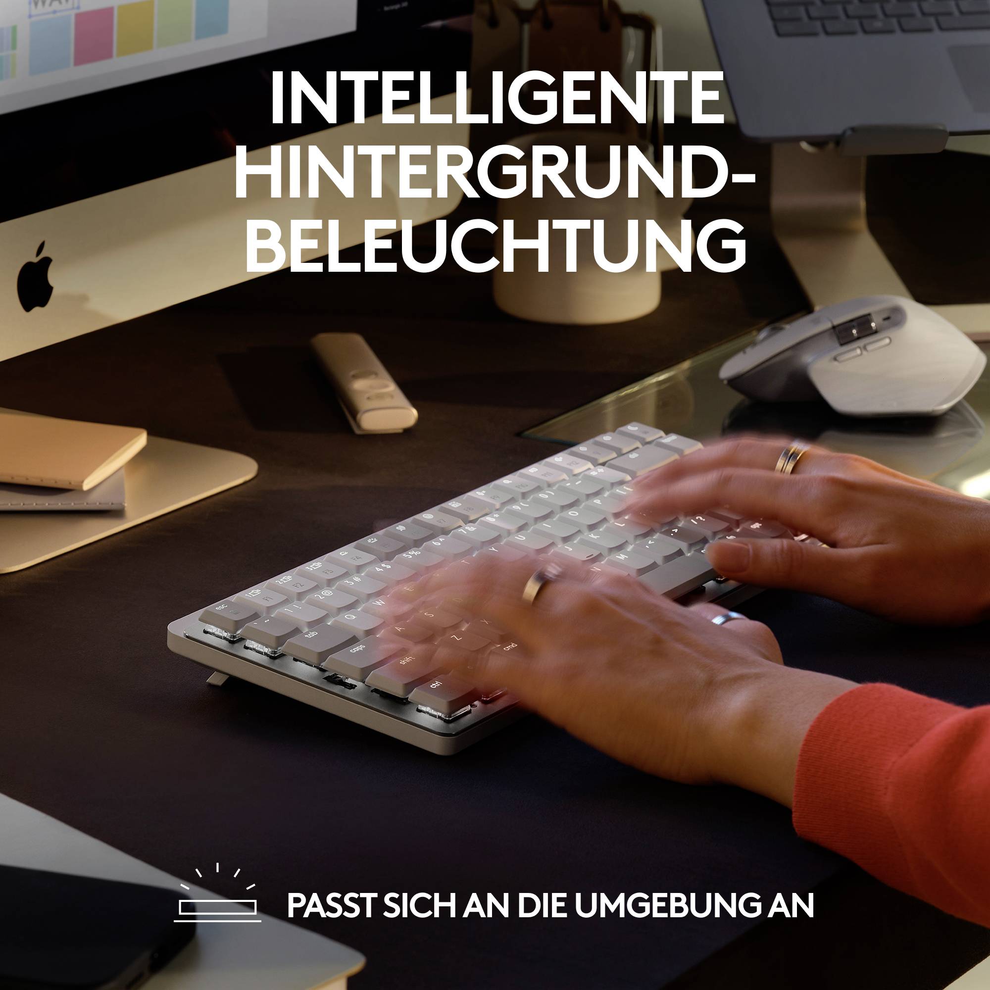 Twee handen typen op een verlicht toetsenbord. De tekst 'Intelligente achtergrondverlichting. Past zich aan de omgeving aan' staat bovenaan de afbeelding.