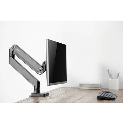 Monitorarm met gemonteerd scherm op een houten bureau, naast een toetsenbord en schrijfgereedschappen; minimalistische kantoorinrichting.