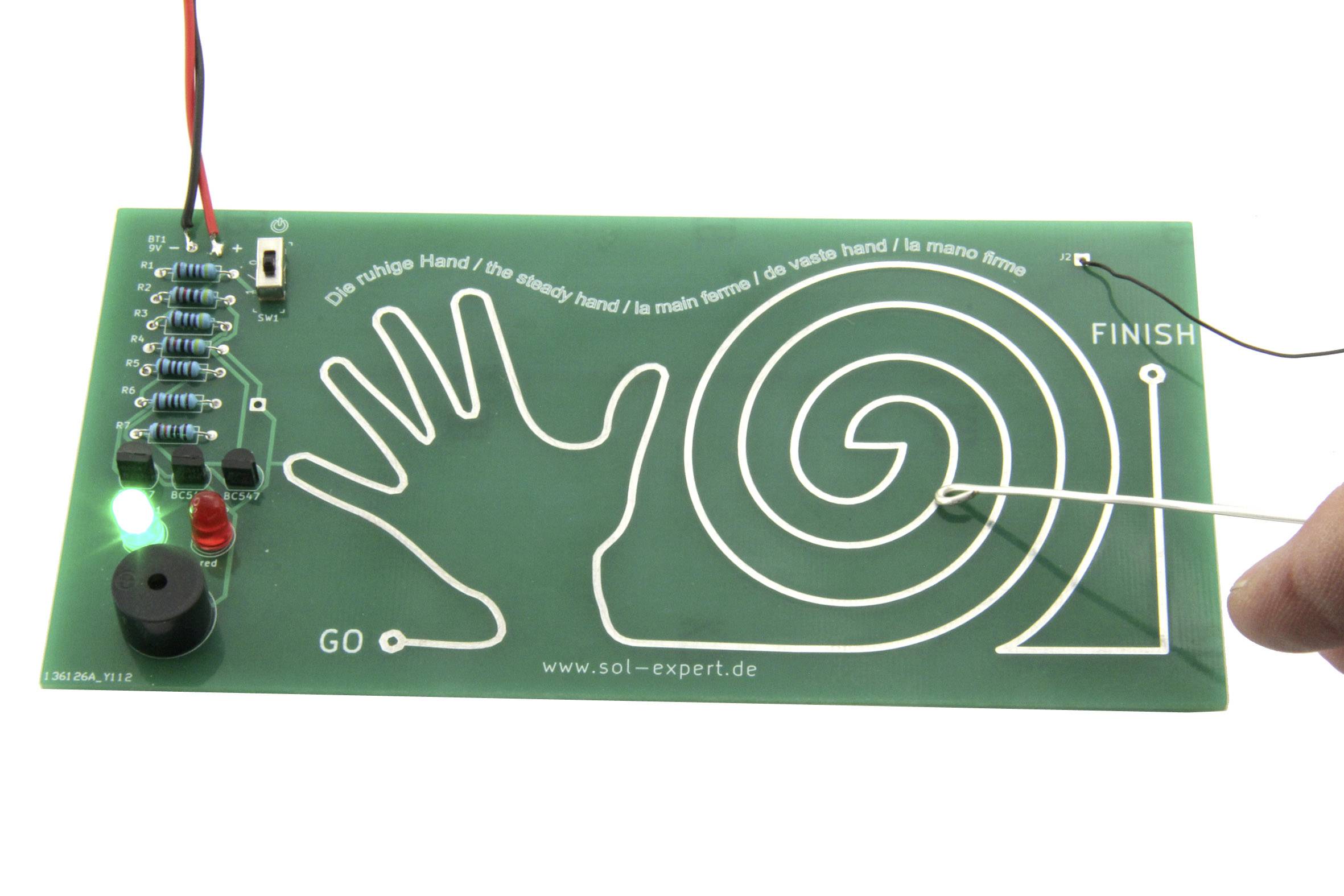 Groen elektrisch behendigheids- en vaardigheidsspel met een handcontour en een spiraalvormig pad; start- en eindpunten gemarkeerd. Een LED licht op.