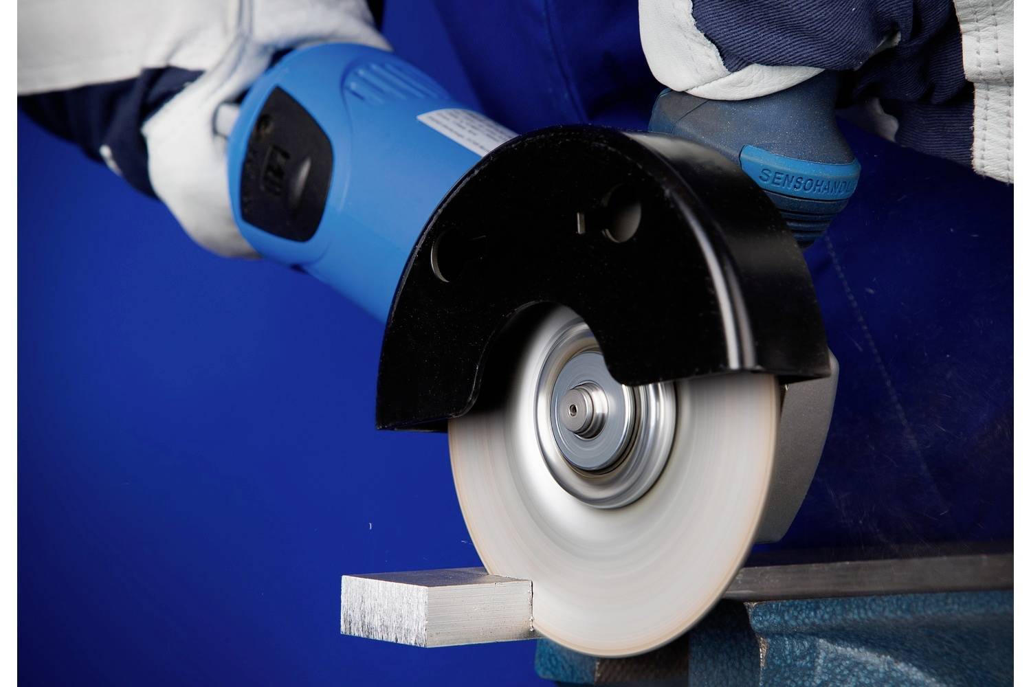 Een persoon gebruikt een elektrische slijpmachine om een metalen rand te slijpen. De machine produceert vonken.