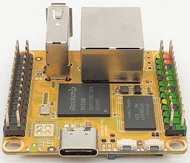 Een klein, oranje computerbord met chips, een USB-C-aansluiting en meerdere pinnen voor elektronische verbindingen.
