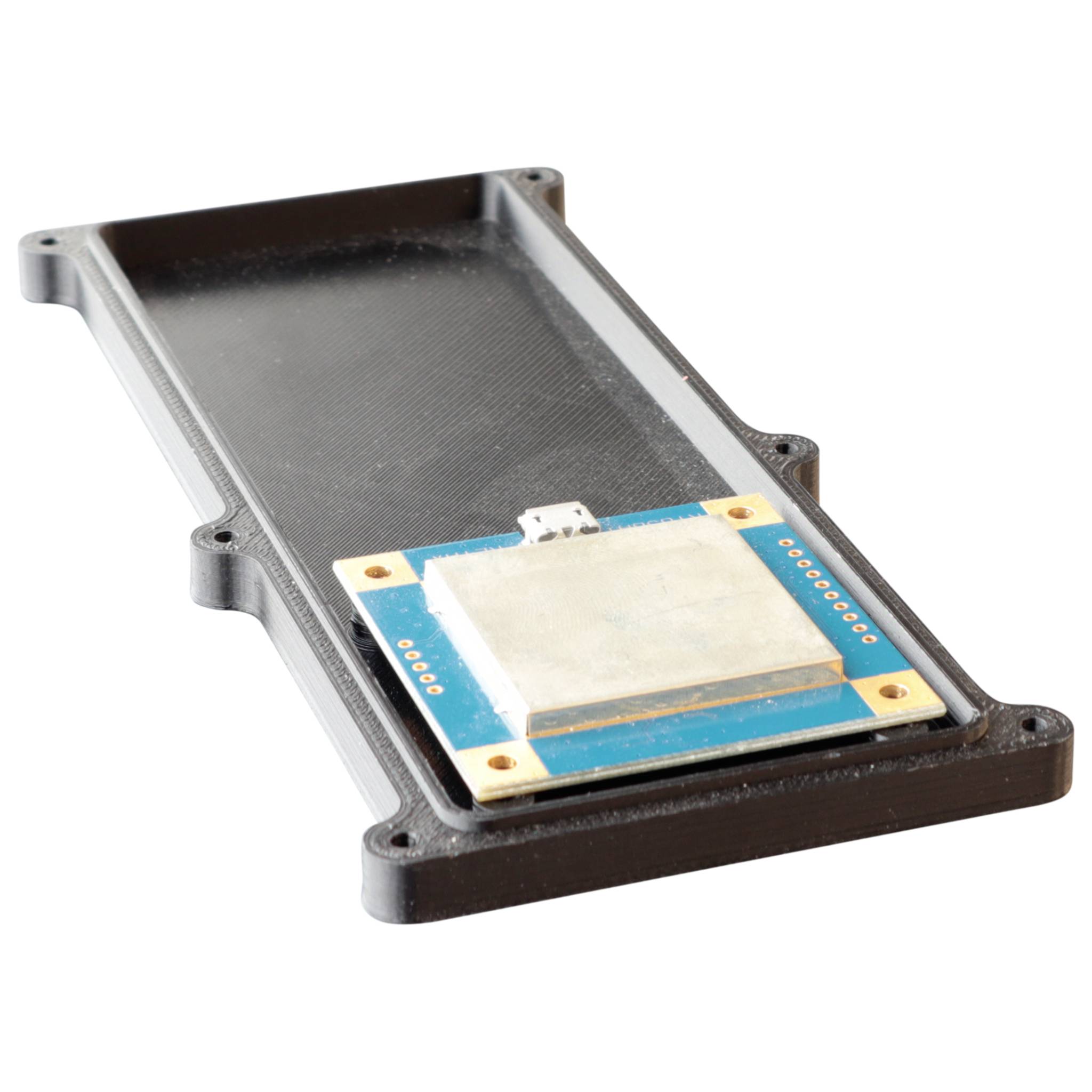 Een elektronische module met een metalen plaat op een blauwe printplaat, gemonteerd in een zwarte behuizing, diagonaal gefotografeerd.
