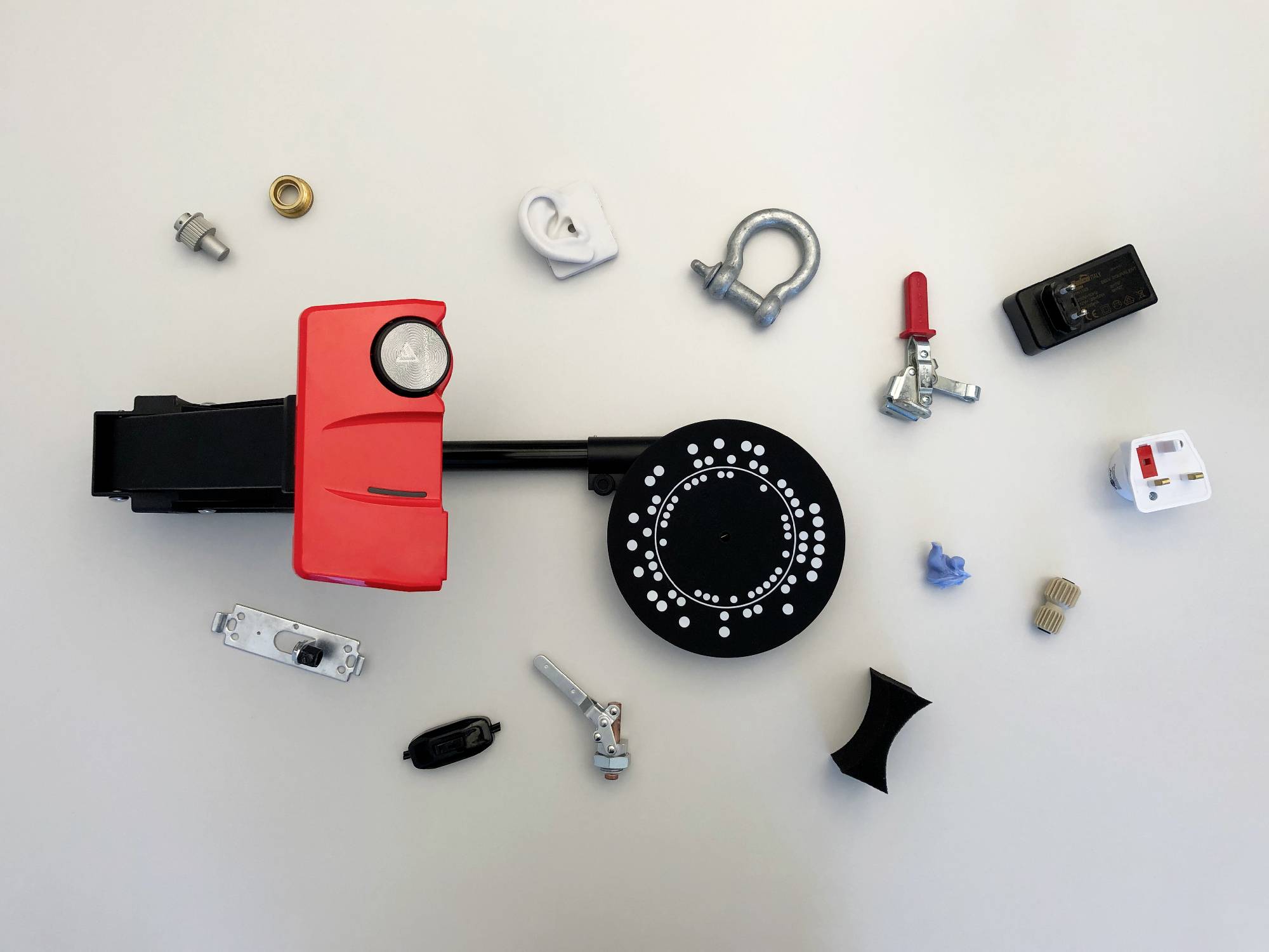 Verschillende mechanische en elektronische componenten, los gerangschikt op een tafel, waaronder tandwielen, schakelaars en bevestigingsonderdelen.