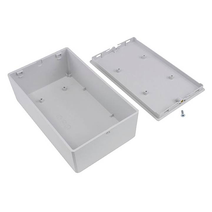 Grijze rechthoekige kunststof behuizing met verwijderde deksel, bekeken van bovenaf. Een schroef ligt ernaast.