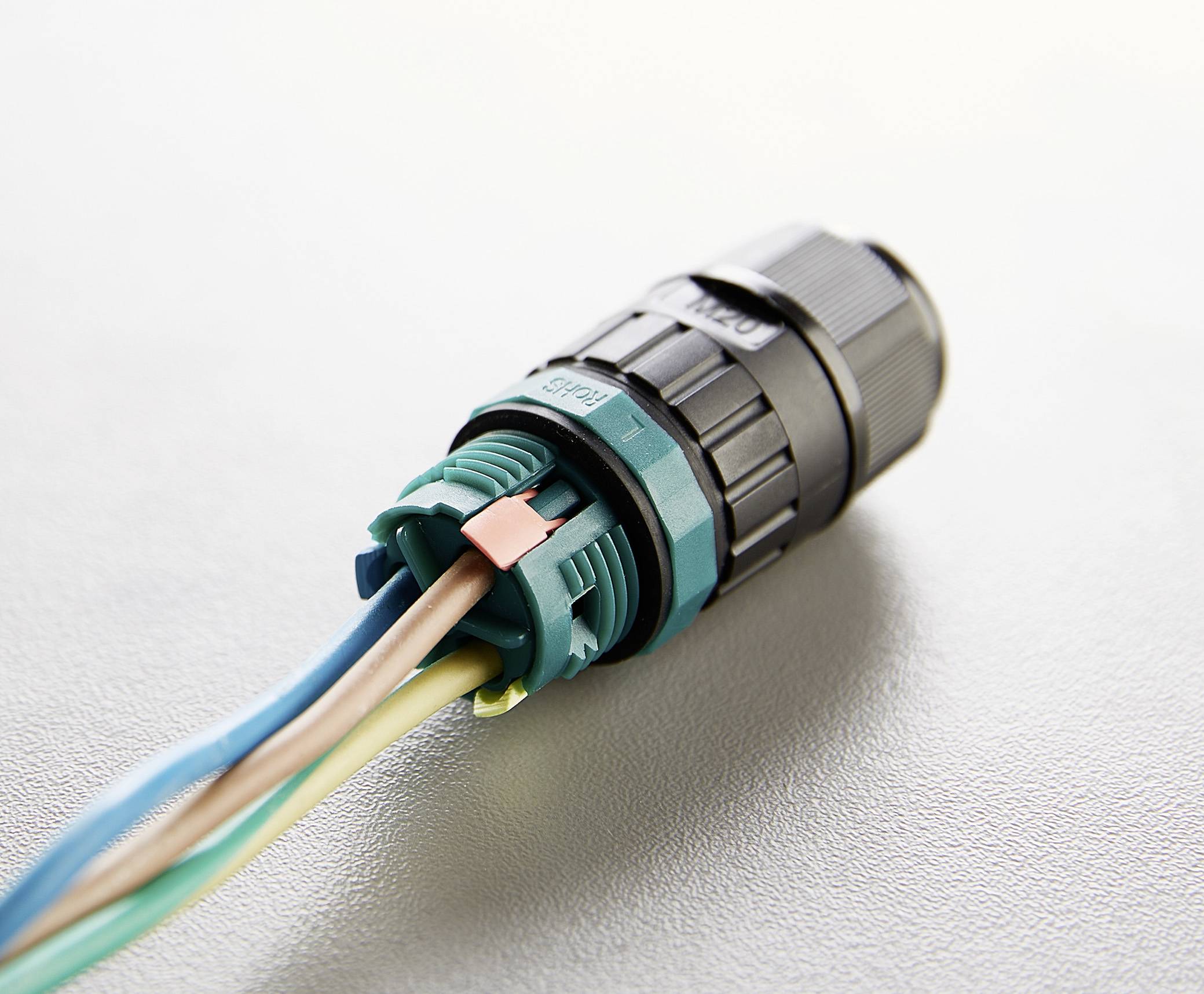 Een close-upfoto van een elektronisch verbindingselement met verschillende kabels in blauw, bruin en geel-groen die eraan zijn bevestigd.