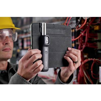 Een persoon houdt een tablet vast met een opzetstuk voor het meten van elektrische installaties, terwijl hij een kabelsysteem controleert.