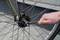 Een hand draait met een moersleutel de moer op de achteras van een fiets vast.