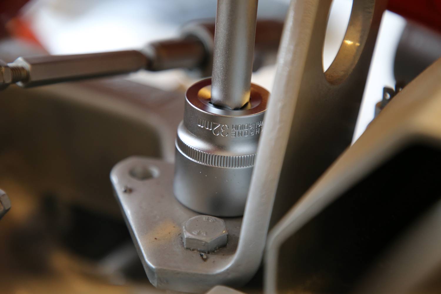 Een zilveren moersleutel draait een moer op een metalen beugel. Mechanisch werk in beeld.