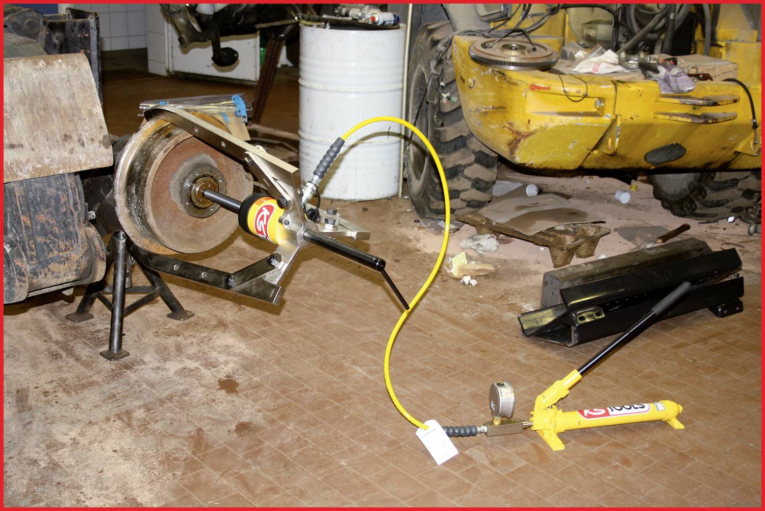 Een werkplaats met een hydraulische persgereedschap dat is bevestigd aan een grote metalen constructie. Op de achtergrond zijn machines te zien.