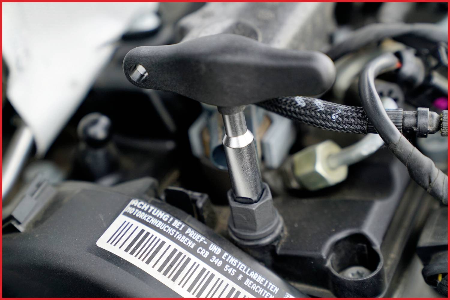 Een momentsleutel wordt gebruikt voor het aantrekken van een schroef aan een motor. Barcode en tekst zijn gedeeltelijk zichtbaar.