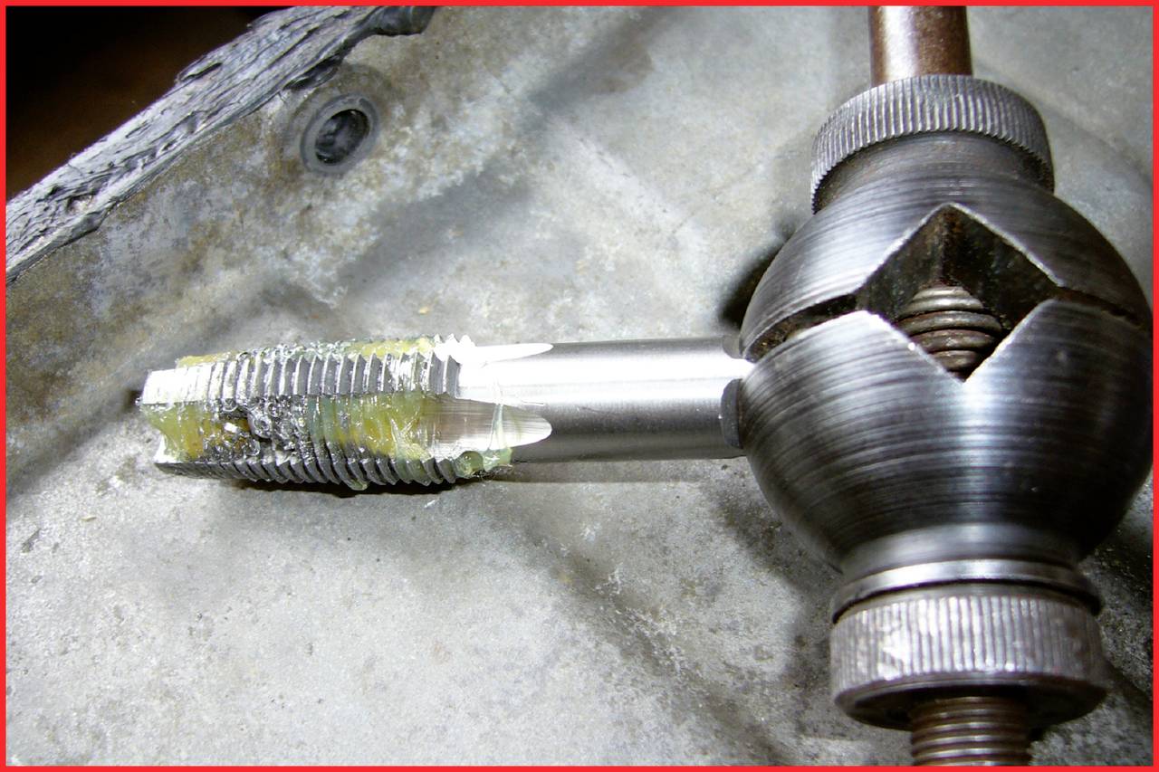 Een snijgereedschap met een draadtap bewerkt een metalen werkstuk. Het toont het gebruik van een gereedschap voor het maken van schroefdraad.