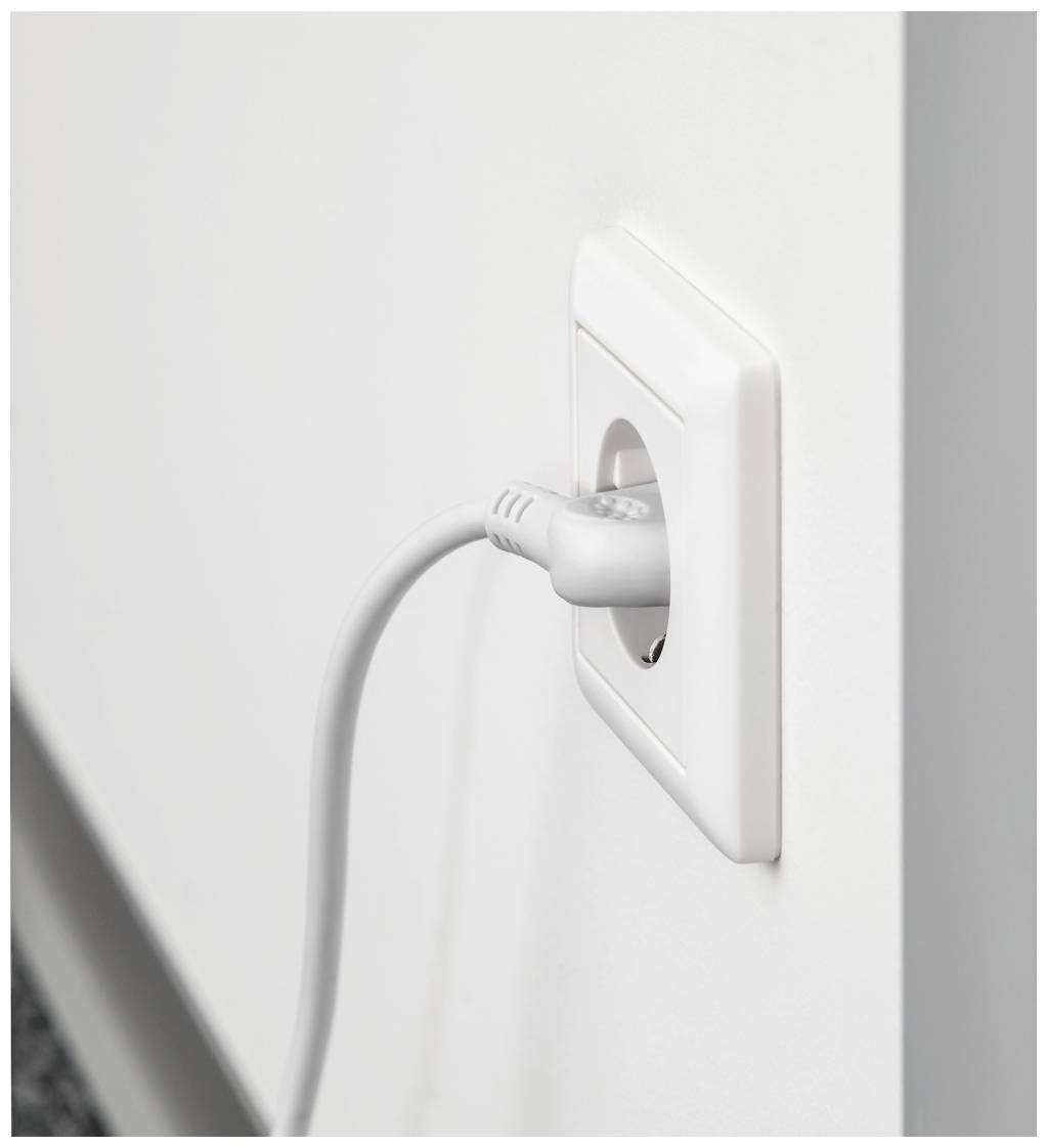 Een witte wandcontactdoos met een ingestoken grijs stroomsnoer. Het snoer loopt naar beneden, de muur is licht en glad.
