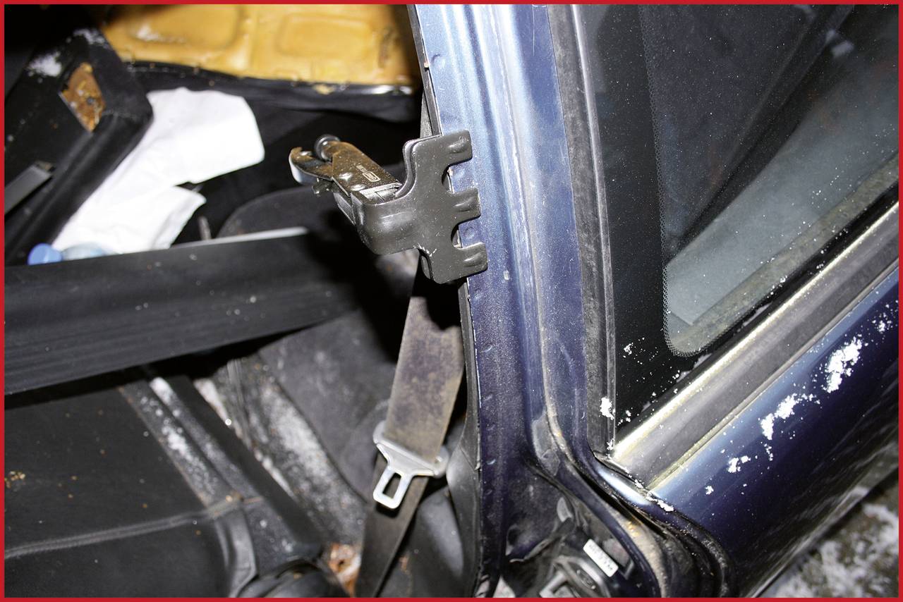 Een beschadigde auto-interieur met een versleten veiligheidsgordel en een gebroken zijruit.