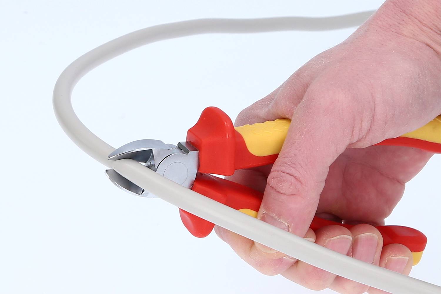 Een hand houdt een zijkniptang en knipt een kabel door.
