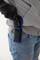Persoon in blauwe spijkerbroek draagt een grijs sweatshirt en trekt voorzichtig een zwart mes uit een blauwe holster aan de broek.
