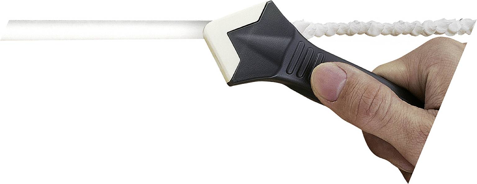 Een hand houdt een kunststof gereedschap vast dat wordt gebruikt om overtollige afdichtkit van een voeg te verwijderen en glad te strijken.