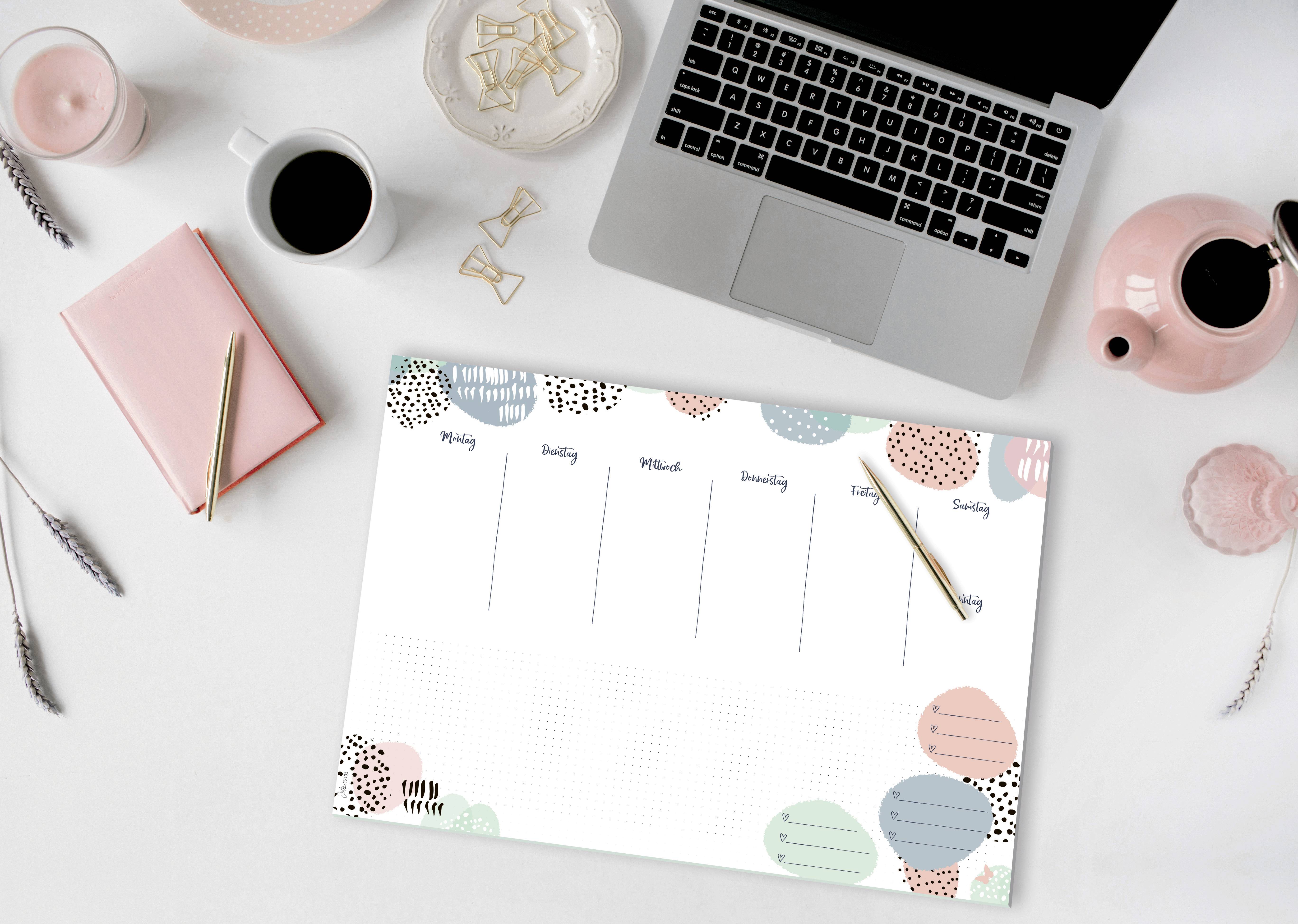 Laptop op een bureau met een weekplanner, koffiekopje en notitieboek. Perfect voor kantoororganisatie en afspraken plannen.