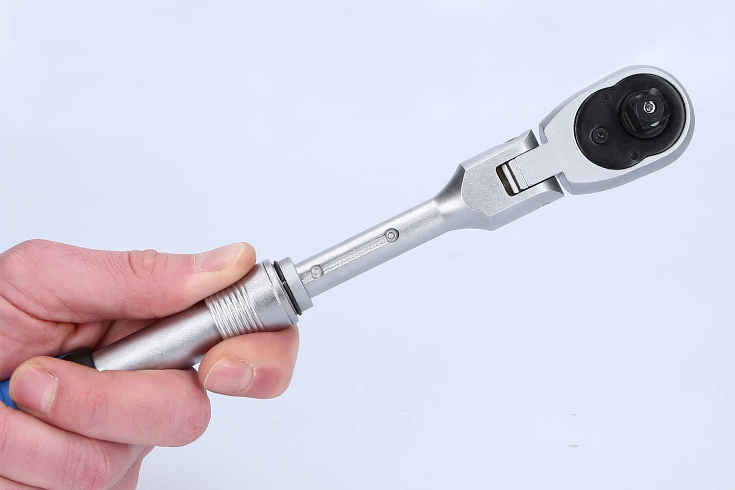 Een hand houdt een ratel met zilveren handgreep voor een neutrale achtergrond.