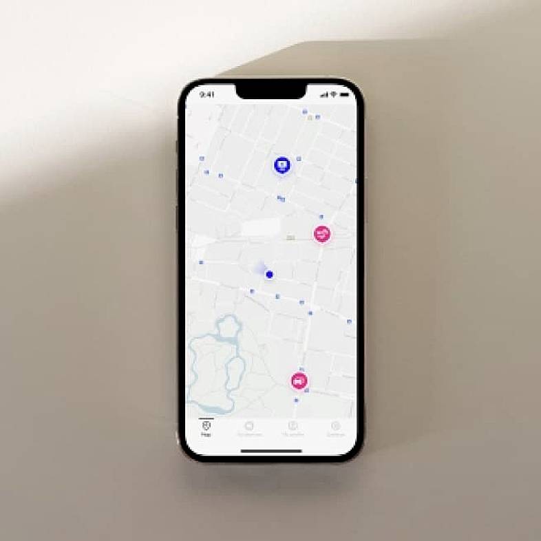 Smartphone toont een kaart-app met meerdere gemarkeerde locaties, waaronder blauwe en roze symbolen. Hij bevindt zich op een tafel.