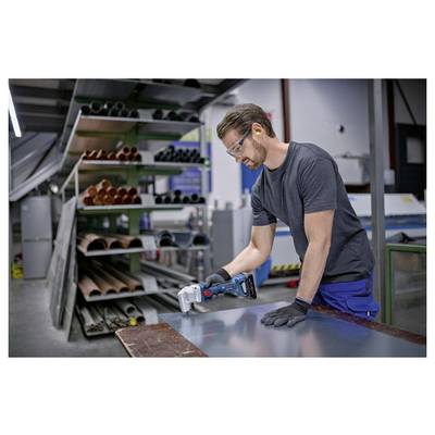Een werker die een veiligheidsbril en handschoenen draagt, gebruikt een elektrische schuurmachine op een metalen plaat in een werkplaats.