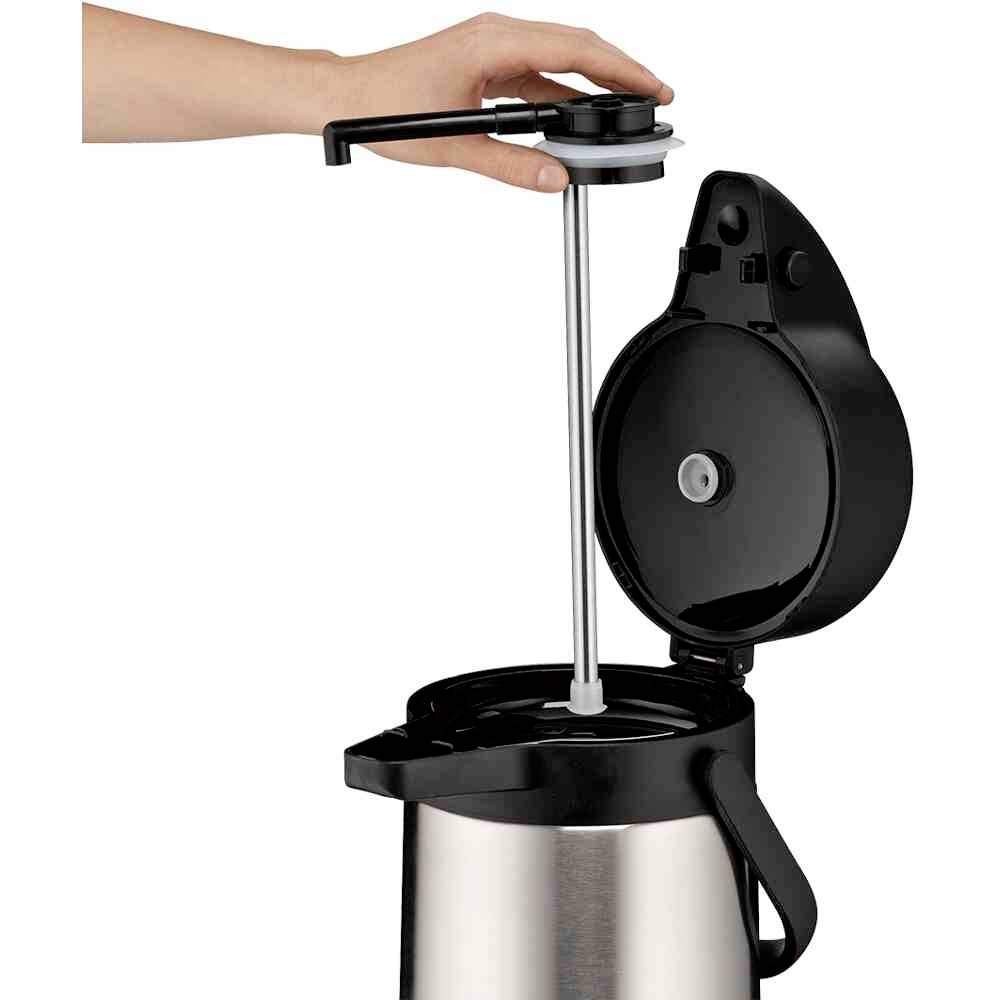 Een hand bedient de pomp van een zilveren Airpot-koffiekan met geopend deksel.