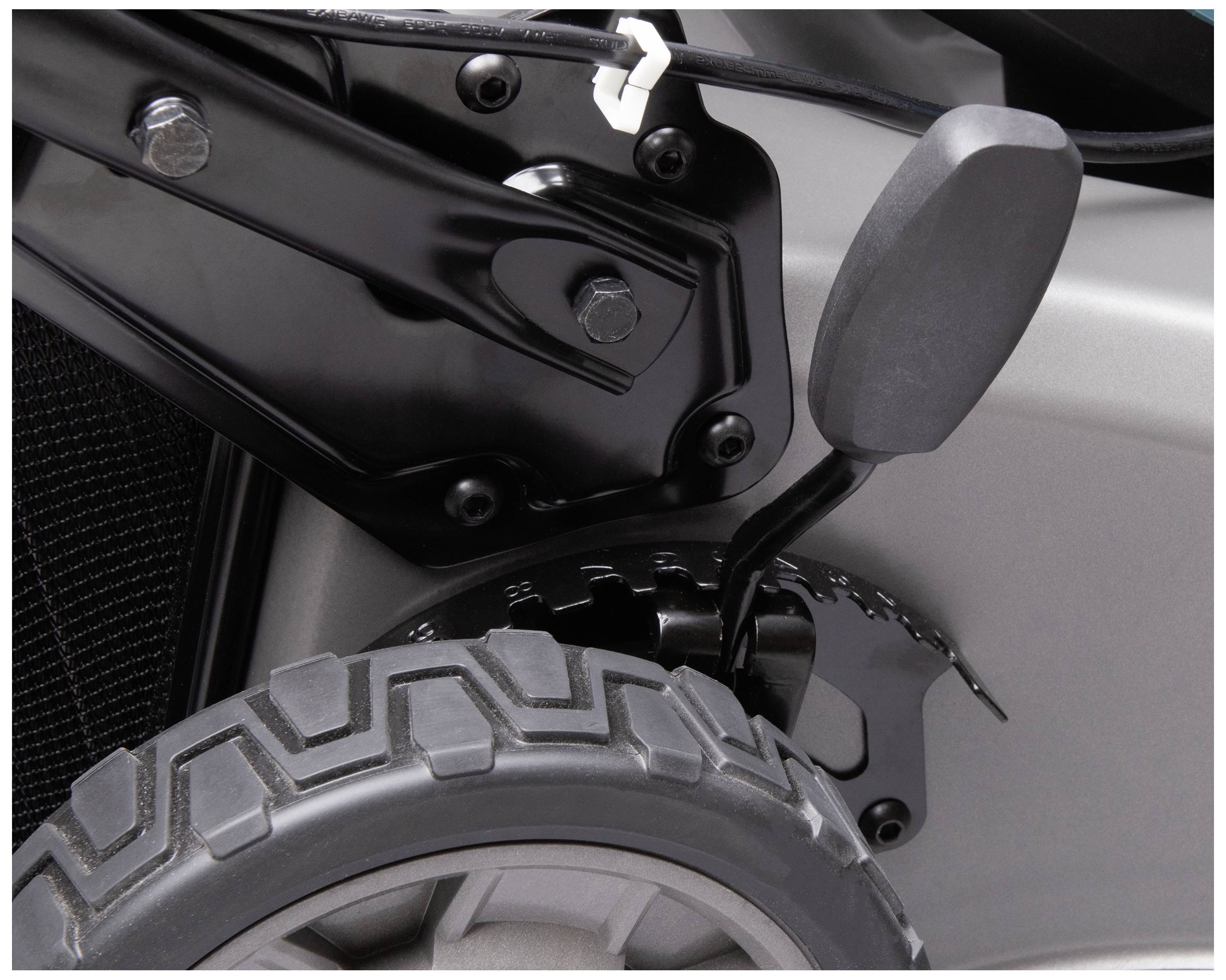 Close-up van een deel van een rolstoel met een robuust zwart metalen frame en geprofileerd wiel. De verbinding en bevestiging zijn zichtbaar.