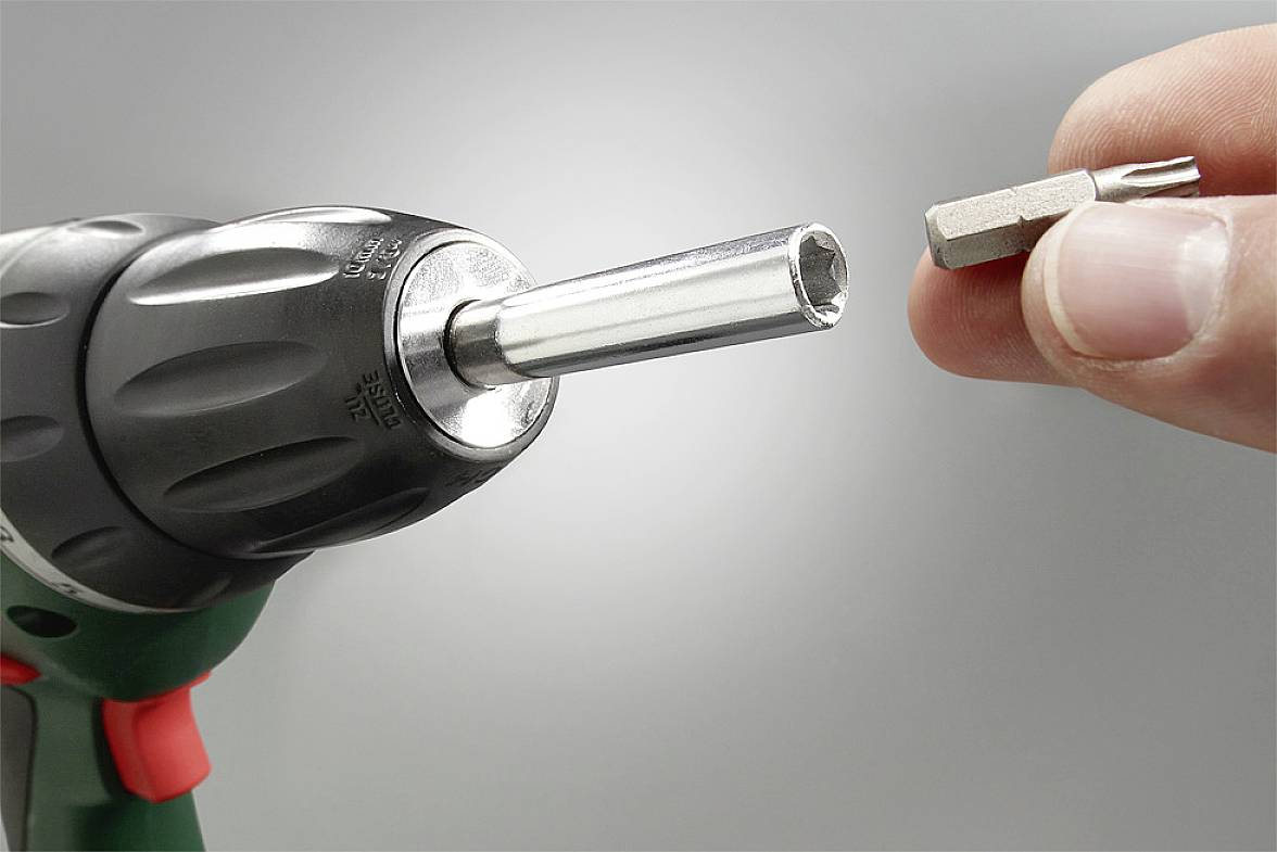 Accuschroefboormachine met verwijderde bit, klaar om te verwisselen, gefocust op een boorkop en bit in één hand.