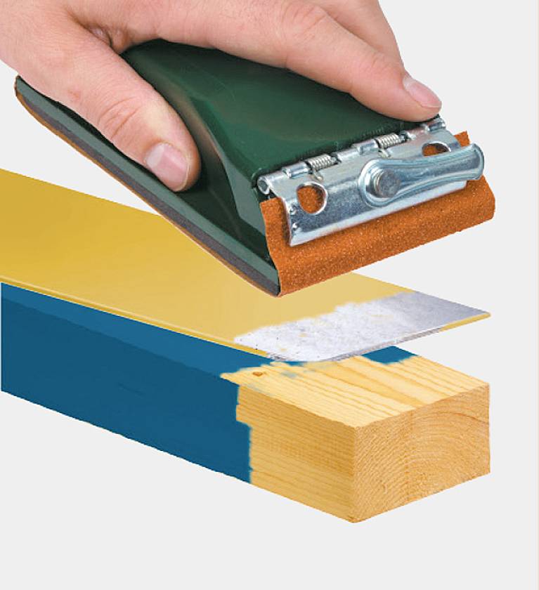 Een hand gebruikt een schuurgereedschap op een stuk hout om verf van het oppervlak te verwijderen.