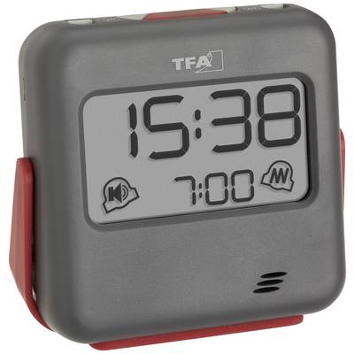 Digitale klok met groot display toont '15:38'. Een wekker-symbool onderaan geeft de alarmtijd '7:00' aan. De behuizing is grijs met rode accenten.