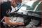 Een monteur luistert met een stethoscoop naar de motor van een auto om een mechanisch probleem te diagnosticeren.