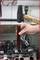 Een hand houdt een klep vast die met een hamer in een motorblok wordt geslagen; toont een stap van de motorreparatie.