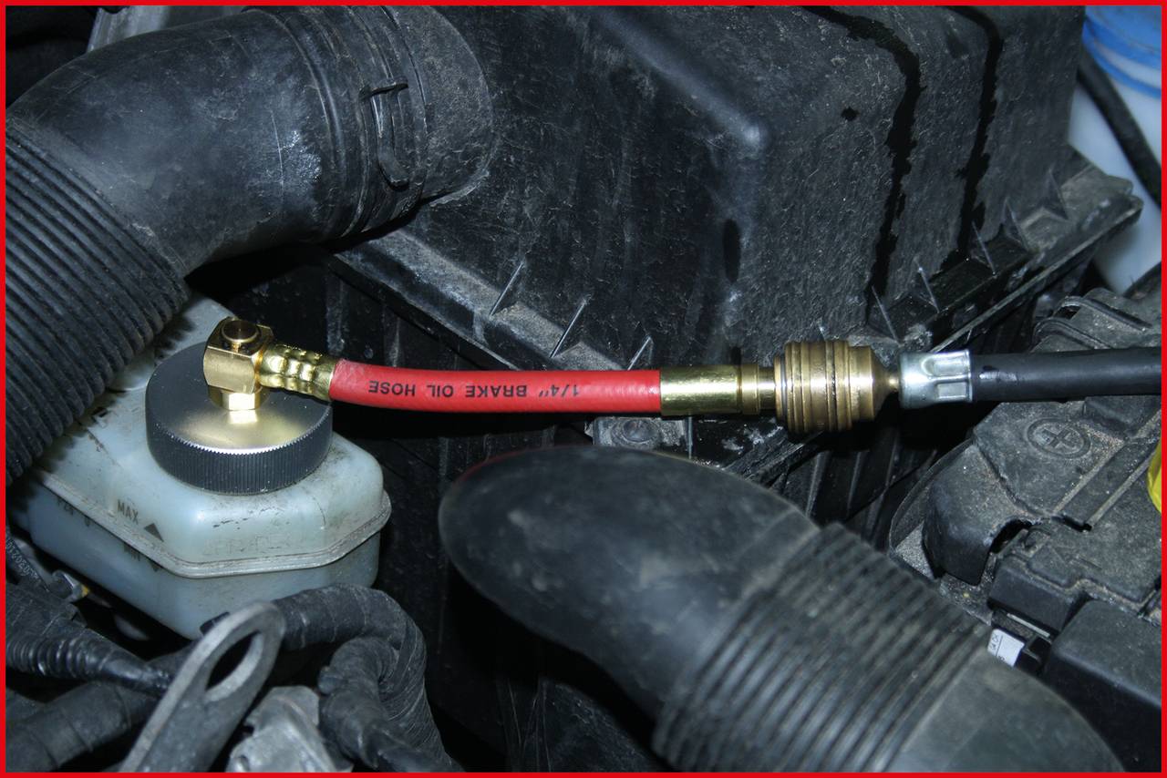 Meetinstrument voor het controleren van de remvloeistofdruk, aangesloten op een reservoir in de motorruimte van een voertuig.