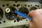 Een hand houdt een gereedschap vast dat in de cilinderkop van een motor wordt gestoken. Het illustreert onderhouds- of reparatiewerkzaamheden.