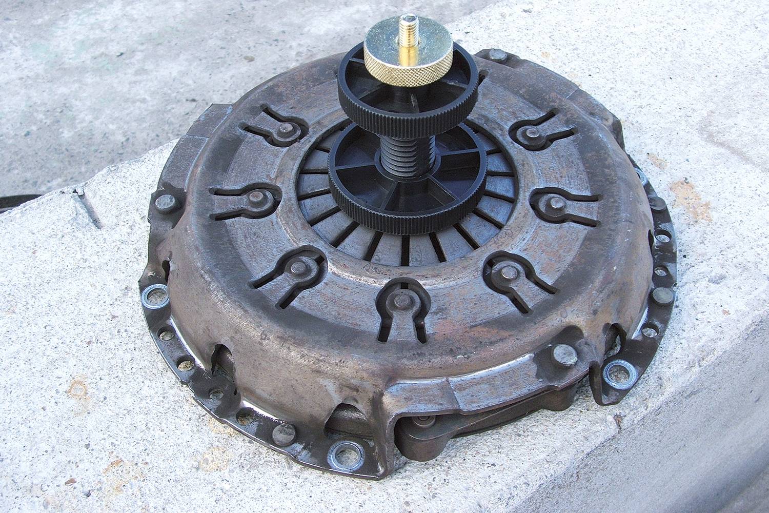 Koppelingsdrukaruk en centreertoestel liggen op beton. De onderdelen zijn bedoeld voor reparaties of vervanging in voertuigkoppelingen.
