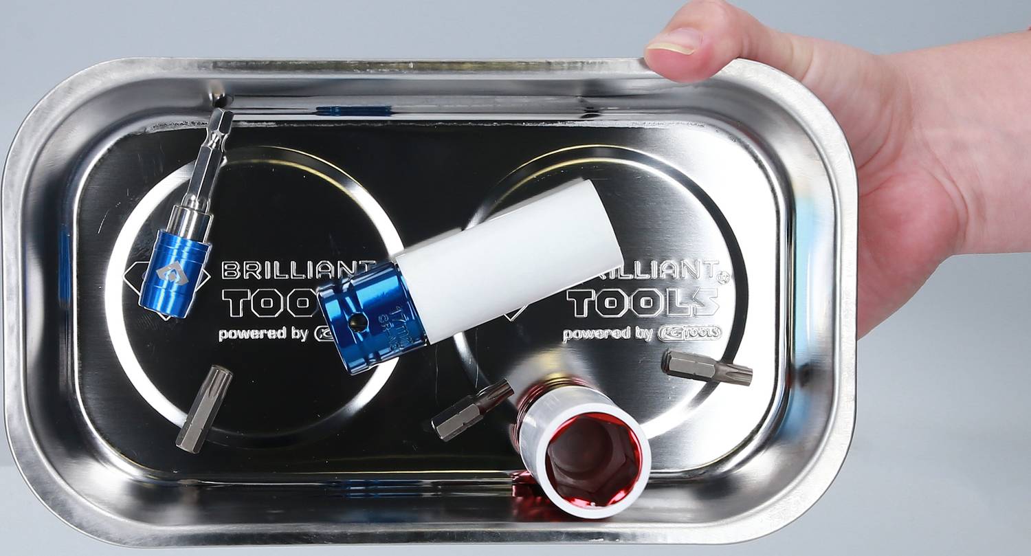 Een hand houdt een magnetisch metalen plateau vast met verschillende gereedschapsopzetstukken, waaronder blauw en rood gemarkeerde bits.
