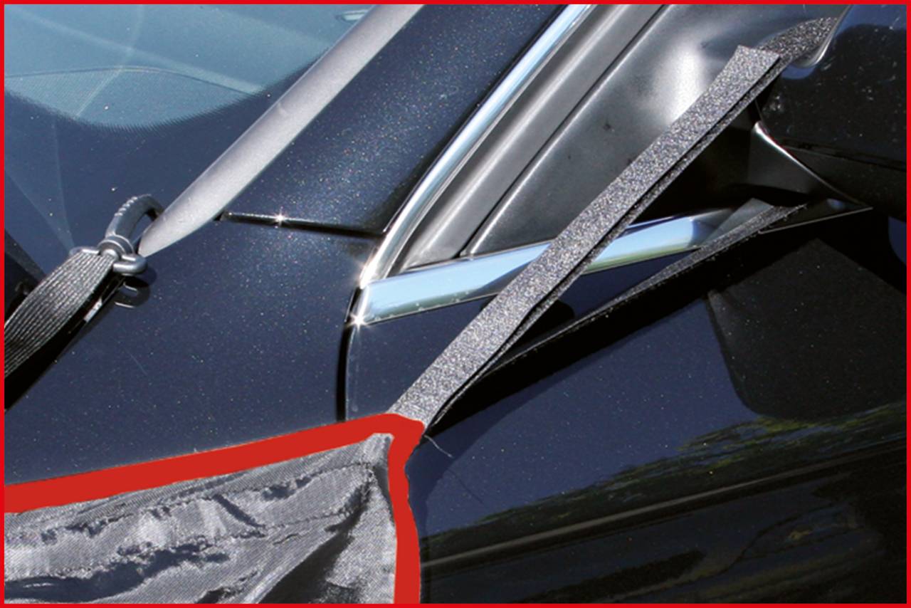 Close-up van een zwart auto-onderdeel, waarschijnlijk een autoruit, met een grijs band erover. Het band lijkt bevestigd te zijn.