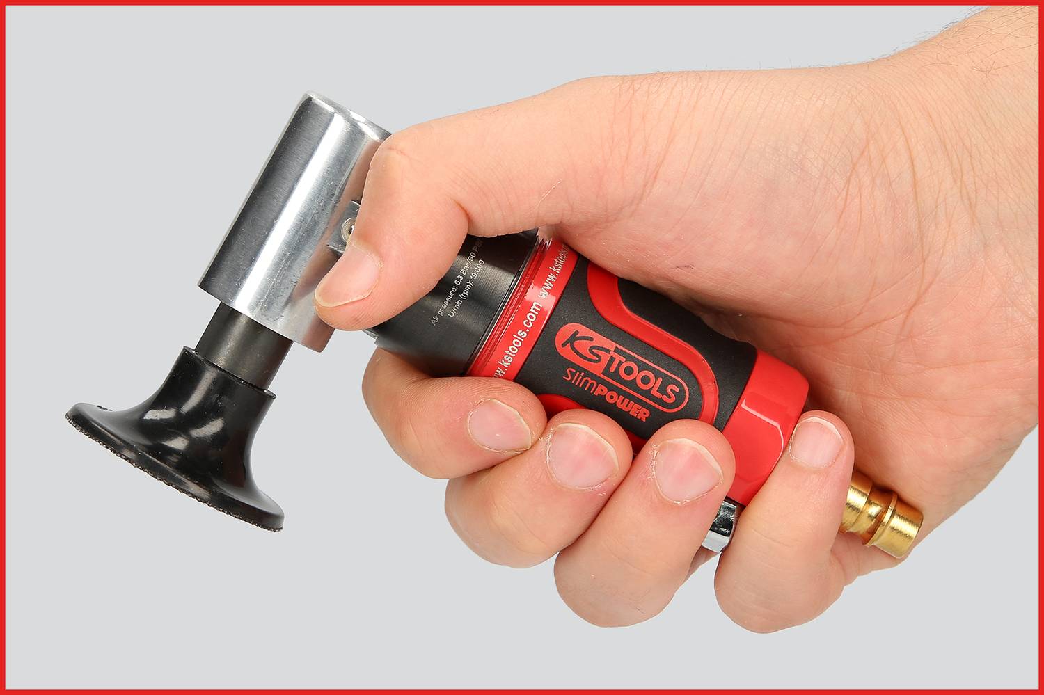Een hand houdt een rode pneumatische tool van KS Tools met een rond zwart opzetstuk, klaar voor gebruik.