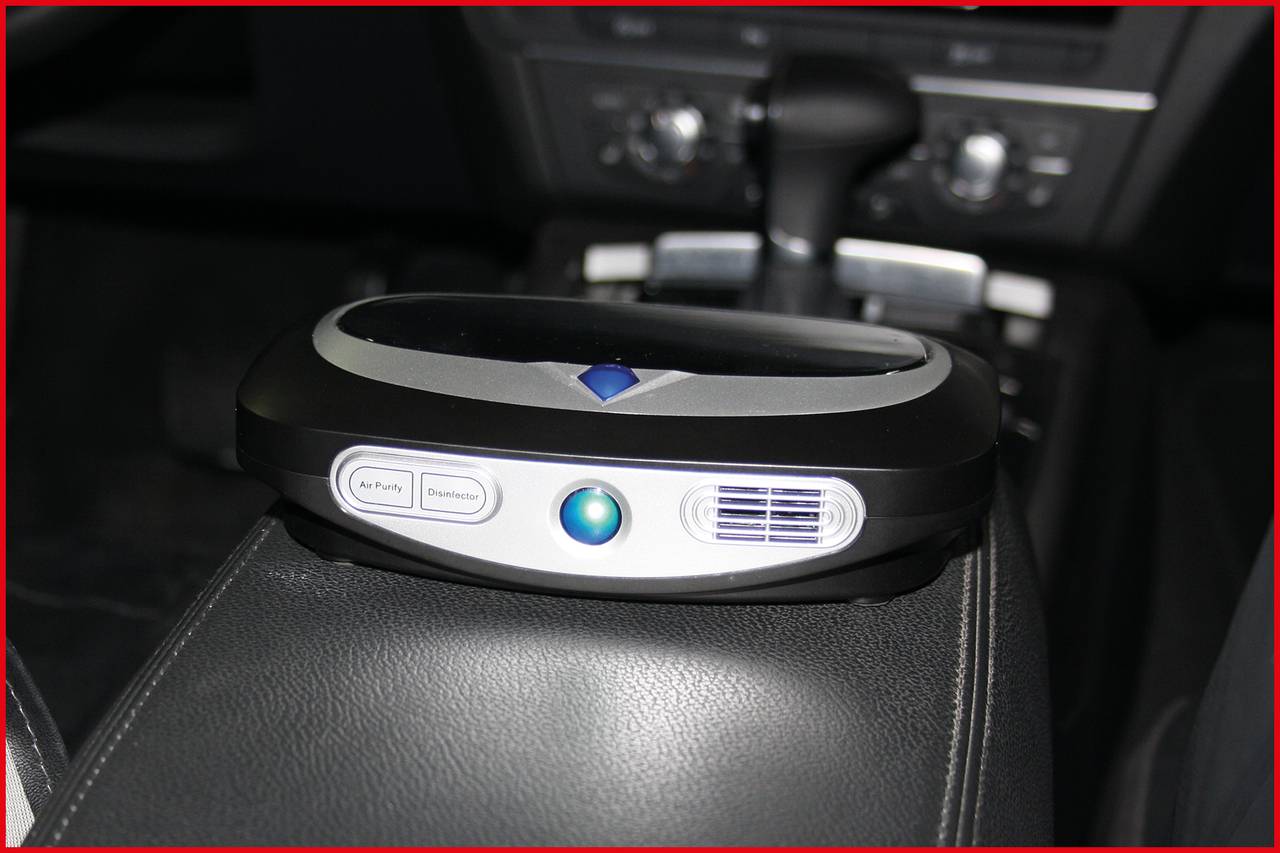 Een luchtreiniger op de middenconsole van de auto, met bedieningsknoppen. Op de achtergrond zijn delen van het dashboard zichtbaar.