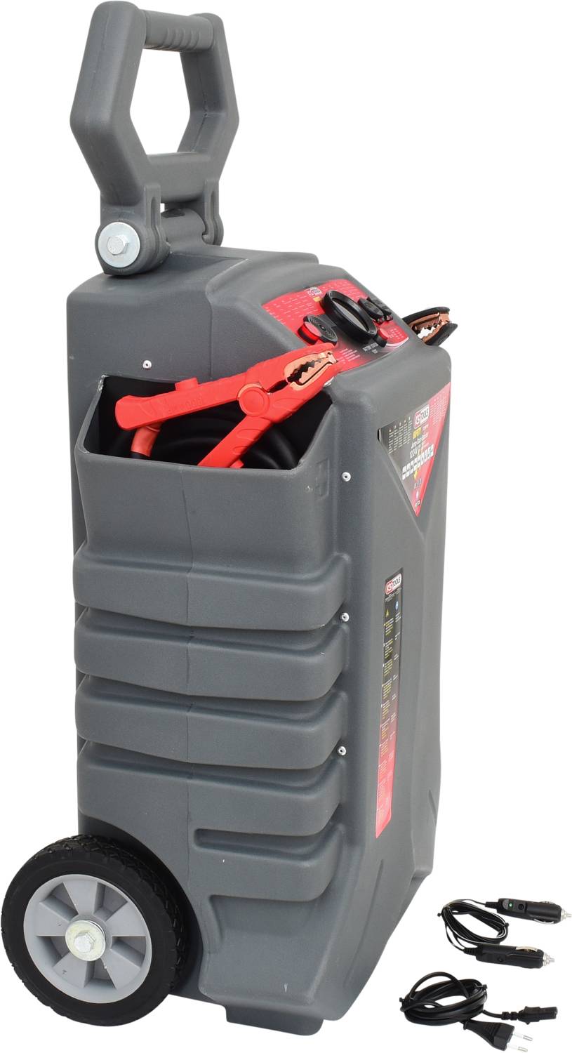 Draagbare jumpstarter op wielen met geïntegreerd kabelopslagvak. Naast de jumpstarter liggen twee kabels met klemmen op de grond.