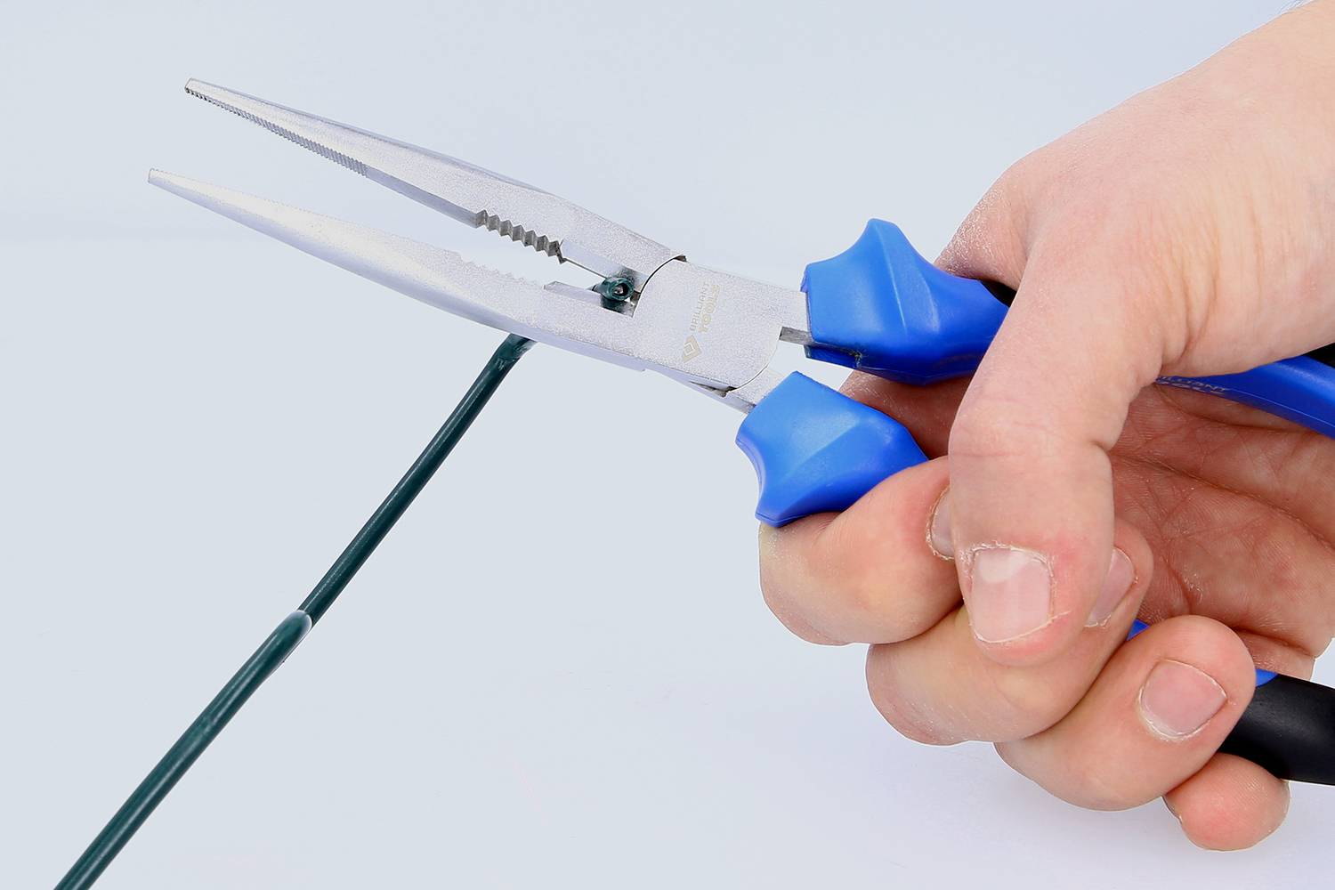 Een hand houdt een tang met blauwe handgrepen en knipt een dunne draad door.